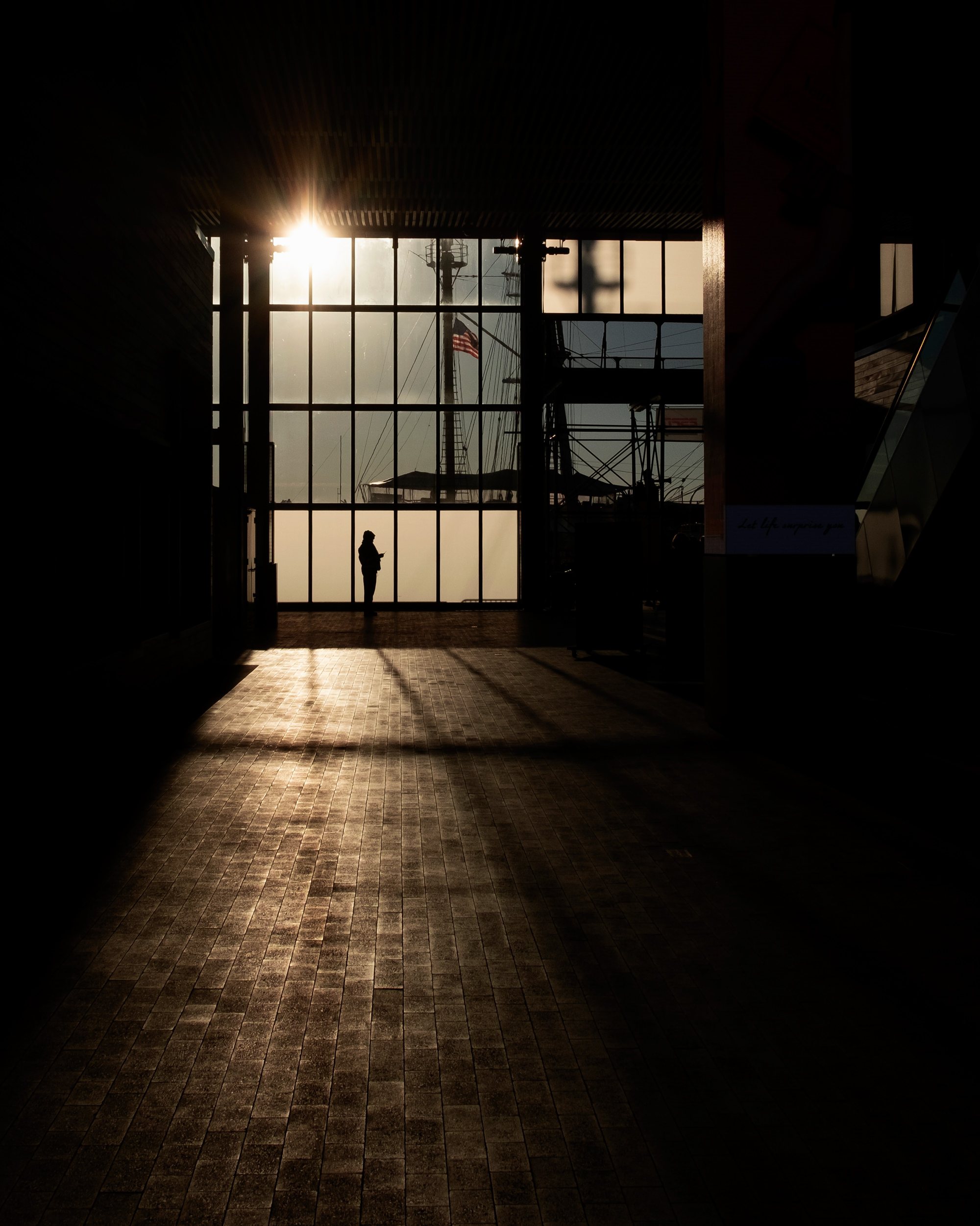 Street photograph by Ahmed Razin, a silhouette in raking light, South Street Seaport, New York